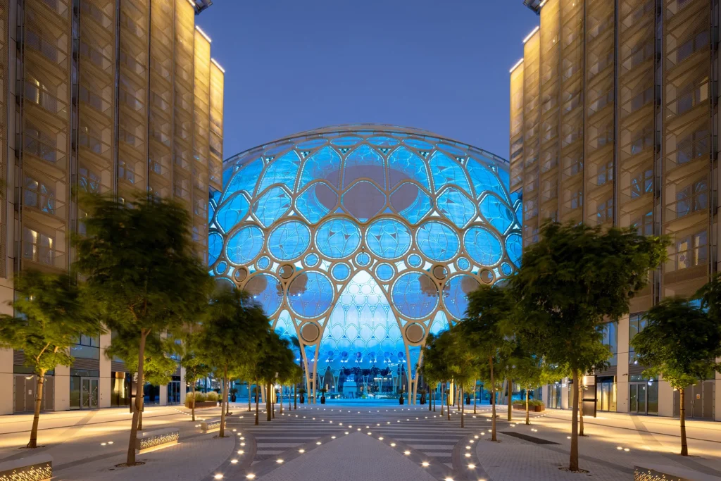 Al Wasl Plaza illuminated dome at Expo City Dubai surrounded by modern buildings.
