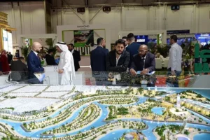 Investors viewing a large Dubai property development model at an international real estate exhibition.